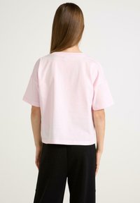 Lyserød cropped t-shirt med korte ærmer, lavet af blød bomuld. Har en simpel rund halsudskæring og ingen synlige mønstre eller logoer.