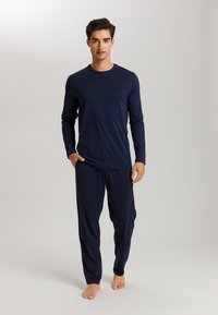 Parte superior de manga larga azul marino y pantalones a juego, confeccionados con una tela suave. El conjunto presenta un ajuste relajado y un diseño simple y sin costuras.
