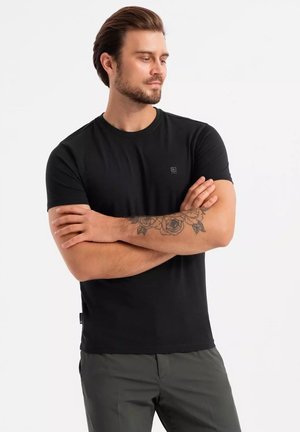 Svart crew neck t-shirt i klassisk passform, tillverkad av mjukt tyg, med en liten logodetalj på bröstet och korta ärmar.