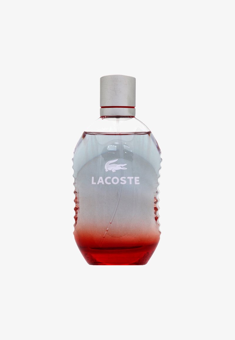 Lacoste parfume flaske med rød gradient væske, klar krop, rillede sider, hvidt logo og sølv låg isoleret på hvid baggrund.