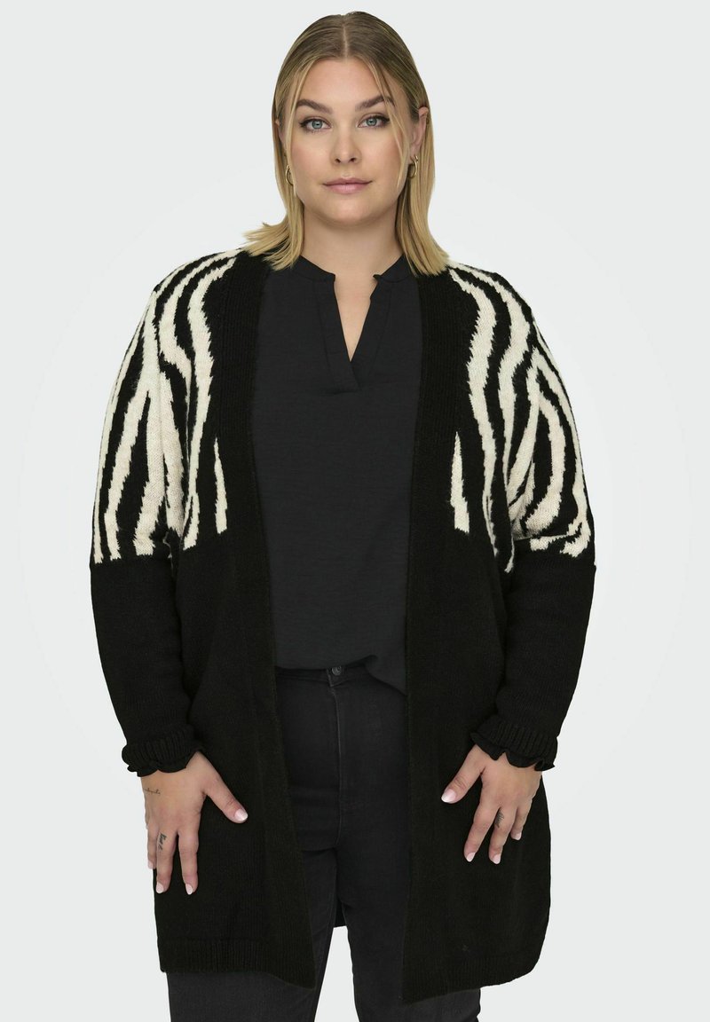 Zwart-wit gebreide cardigan met een zebra-streep patroon op de mouwen, een losse pasvorm en geribbelde manchetten.