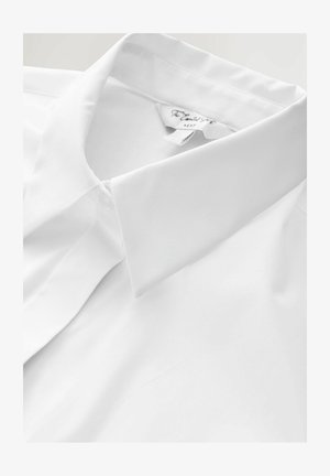 Balta kokvilnas krekls ar klasisku apkakli, gludu tekstūru un bez redzamām rakstiem. Apkakles smalkas šūšanas detaļas. Etiķete "Next".