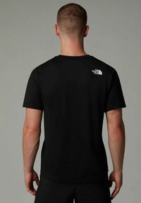 Camiseta negra de manga corta con cuello redondo y un logo blanco en la parte superior de la espalda, hecha de una tela suave.