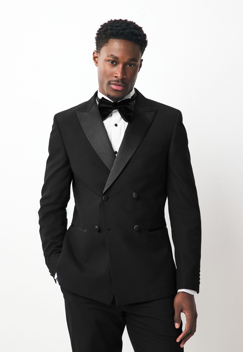 Black double-breasted tuxedo jacket with satin lapels, paired with a white shirt and black bow tie. Smooth fabric, fitted design, no visible patterns.