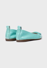 Bailarinas de cuero turquesa con un acabado suave, punta redondeada y un pequeño tacón. Cuentan con una lengüeta para facilitar su uso y una suela de goma marrón.