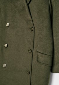 Dvojno zapenjanje zeleni volneni plašč z metalnimi gumbi, sprednjim žepom in strukturiranimi reverji. Gladka tekstura in krojena zasnova.