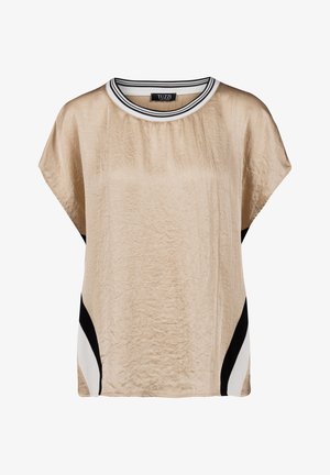 Beige blouse met korte mouwen en een gekreukte textuur, zwarte en witte diagonale zijpanelen, en een witte halslijn met zwarte strepen.