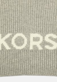 Écharpe en tricot grise avec une texture côtelée et un texte logo en crémeux audacieux. Le matériau semble doux et chaud, idéal pour les temps froids.