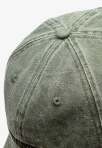 Zielona czapka z daszkiem z sztruksu, z zaokrągloną koroną, widocznym przeszyciem oraz sześcioma otworami wentylacyjnymi dla lepszej oddychalności.