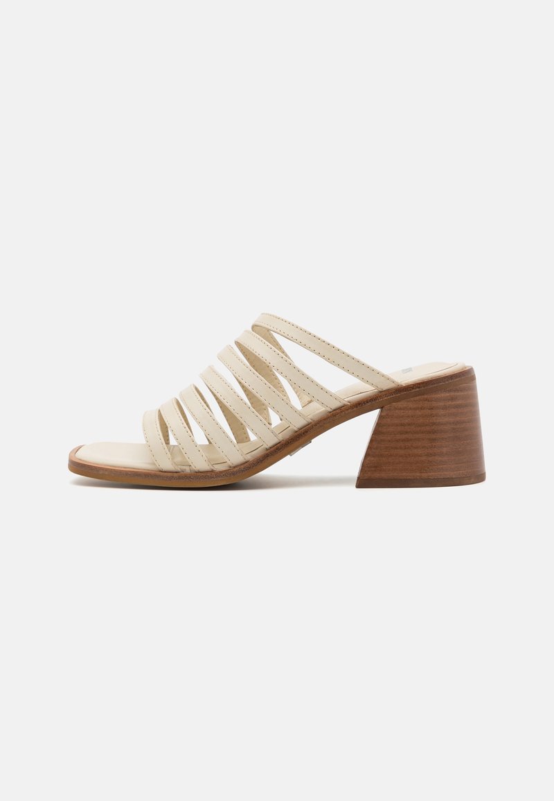 Sandale beige à bout ouvert avec plusieurs lanières horizontales et un large talon bloc en bois empilé sur un fond uni.