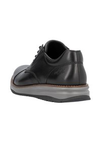 Zapato de vestir de cuero negro con acabado liso, suela de goma gris, costuras visibles y detalle de logo en el talón. Diseño de punta redonda.