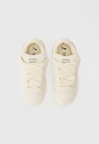 Kreminės drobės sportinės bateliai su storomis raišteliais, paminkštintu liežuviu ir guminėmis padangomis. Ant liežuvio ir įdėklų yra "Puma" logotipas. Suplokščias pirštų dėklas.