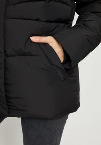Schwarze gepolsterte Jacke mit Seitentasche; glatte Textur; hat einen hohen Kragen und eine taillierte Silhouette.