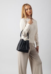 Black leather bucket bag with a structured design, short straps, and gold hardware accents. Set against a light gray background.