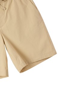 Pantaloni corti beige realizzati in tessuto leggero. Presentano una vita elastica, tasche laterali e una vestibilità ampia con un design che arriva fino al ginocchio.