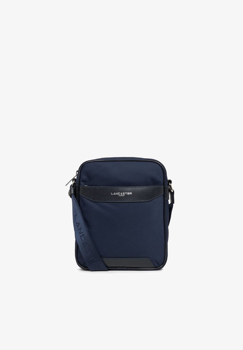 Sac bandoulière bleu marine en nylon avec un accent en cuir texturé. Comprend une poche zippée à l'avant et une sangle ajustable. Logo à l'avant.
