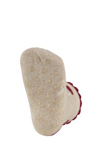 Beige Sock mit roten gewellten Abschlüssen, ausgestattet mit strukturierten Griffpunkten an der Sohle, gefertigt aus einem weichen Strickmaterial mit dekorativen Mustern.