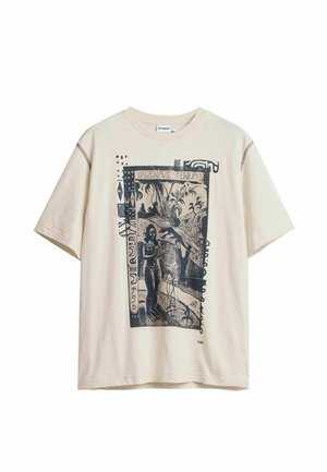 Beige T-shirt met korte mouwen en een zwarte afbeelding van een persoon, planten en abstracte vormen in een rechthoekig kader aan de voorkant.