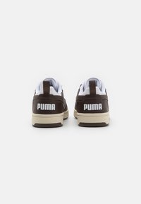 Brune lærersneakers med hvite detaljer, med polstret krage, kontrasterende beige såle og en fremtredende hvit "PUMA"-logo på hælen.