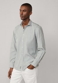Camicia a maniche lunghe a righe in blu chiaro e bianco, con colletto a bottoni, tessuto liscio e design aderente.