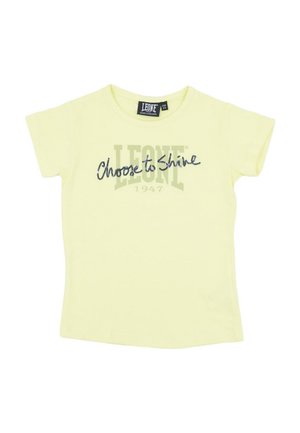 T-shirt jaune pâle à manches courtes avec les inscriptions « LEONE 1947 » et « Choose to Shine » imprimées sur le devant.