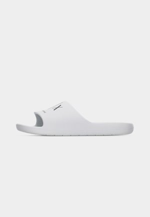 Hvit slip-on sandal med åpen tå og svart "AX"-logo på remmen, vist mot en enkel lys grå bakgrunn.