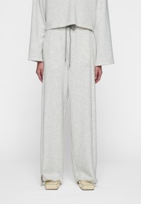 Lichtgrijze lounge set met een cropped top met lange mouwen en broek met koordjes. Zachte textuur en een ontspannen pasvorm met zijsplitten.