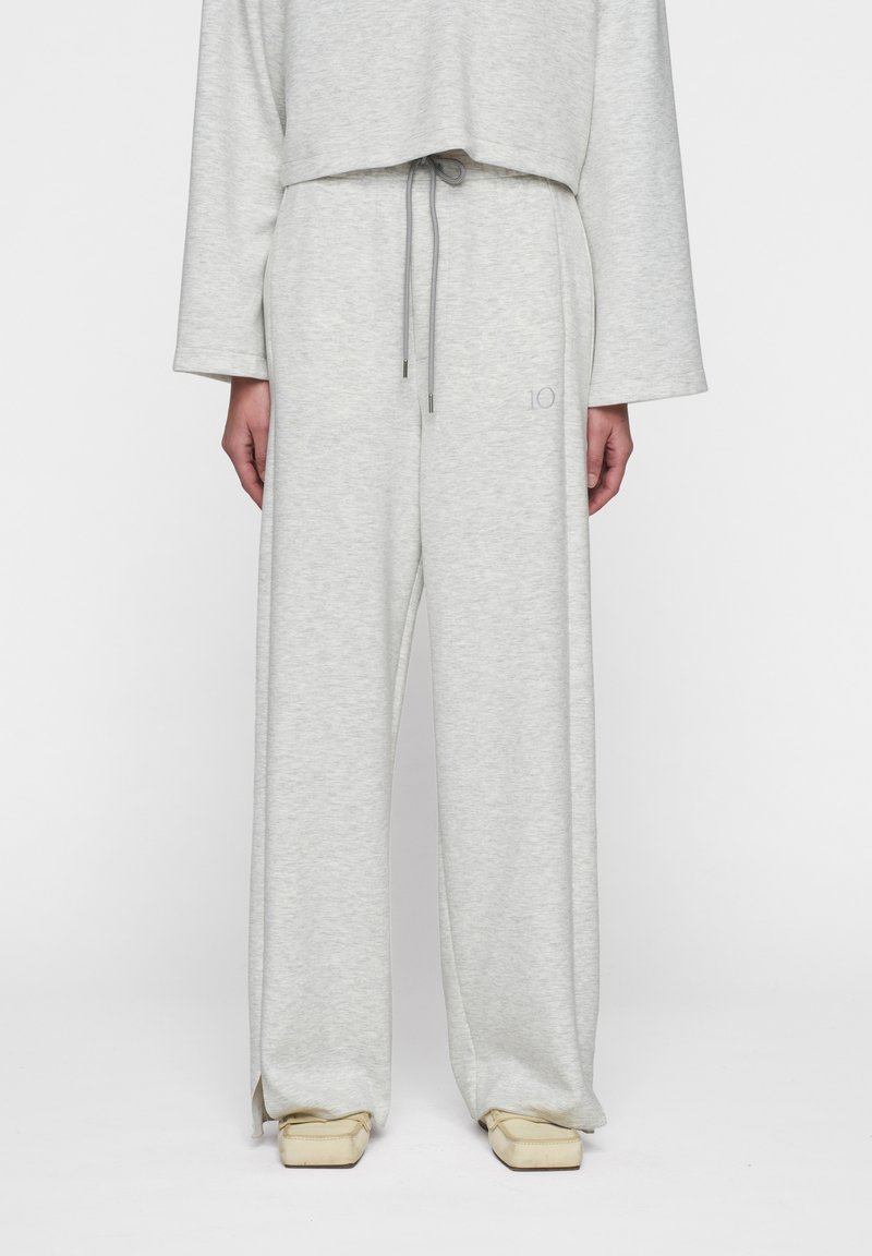 Lichtgrijze lounge set met een cropped top met lange mouwen en broek met koordjes. Zachte textuur en een ontspannen pasvorm met zijsplitten.