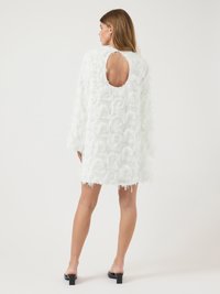 Robe blanche en tissu texturé avec des accents en volants, dotée d'un dos en forme de trou de serrure, de longues manches et d'un ourlet effiloché.