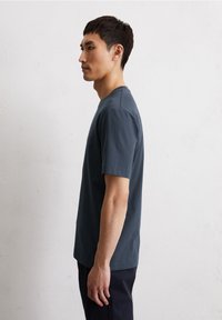 Dunkelblaues T-Shirt mit kurzen Ärmeln aus einem weichen, glatten Stoff. Gerader Schnitt, runder Halsausschnitt, minimalistisches Design ohne sichtbare Logos oder Muster.