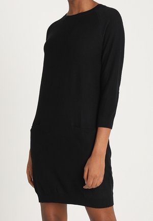 Robe noire en maille avec manches raglan trois-quarts, encolure dégagée et deux poches avant. Comprend des poignets et un ourlet côtelés. Texture douce.