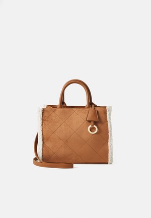 Smeđa jastučićasta suede torba s krznom od ovčje kože, zlatnim metalnim detaljima, dvostrukim ručkama i odvojivim remenom za rame.