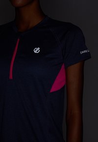 Námořnické sportovní tričko s krátkým rukávem, růžový akcent na boku, přední částečný zip a logo na prsou a rukávu. Hladká textura.