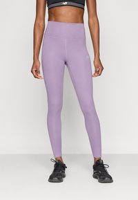 Μωβ κολάν με ψηλή μέση, λεία υφή και εφαρμοστή σχεδίαση. Διαθέτει λεπτομέρεια με λογότυπο σε ανοιχτό γκρι στο ισχίο. Φοριέται με μαύρα αθλητικά παπούτσια.