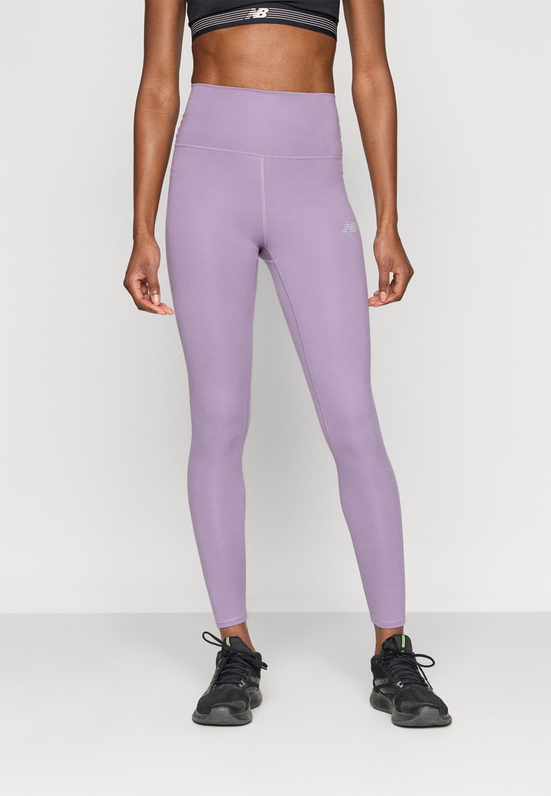 Μωβ κολάν με ψηλή μέση, λεία υφή και εφαρμοστή σχεδίαση. Διαθέτει λεπτομέρεια με λογότυπο σε ανοιχτό γκρι στο ισχίο. Φοριέται με μαύρα αθλητικά παπούτσια.