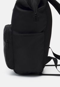 Schwarzer Rucksack mit glattem, Nylon-Außenmaterial, einer seitlichen Netztasche und zwei mit Reißverschluss versehenen Fächern für sichere Aufbewahrung.