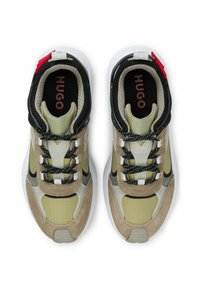 Lace-up sneakers featuring a mix of olive green, black, and beige materials. Textured suede and mesh, with white soles and red accent.