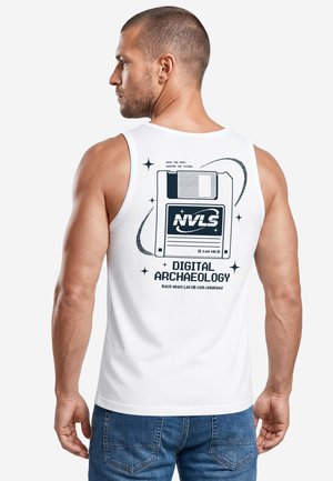 Man seen from behind wearing white sleeveless shirt with a black floppy disk graphic and "Digital Archaeology" text on the back.