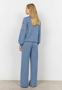 Blue loungewear set featuring a pullover with lace-accented sleeves and matching wide-leg pants, made of soft, textured fabric.