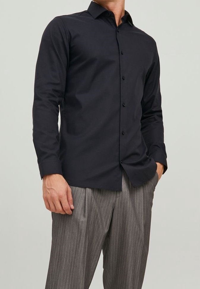 Camisa negra de manga larga ajustada con cuello clásico y botones en la parte delantera, hecha de una tela suave. Combinada con pantalones grises de rayas. 