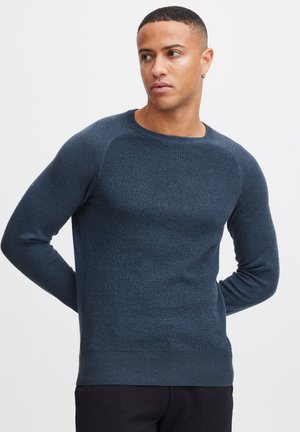 Marineblauer Strickpullover mit langen Ärmeln, strukturiertem Körper, gerippten Bündchen und Saum, Rundhalsausschnitt und nahtlosem Detail an den Schultern.