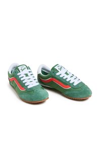 Green suede sneakers with white laces and a red accent stripe, featuring a gum rubber sole and a rounded toe design.