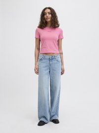 Rosa tettskjorte med tekst, kombinert med lys blå vide jeans. Mørke sko. Enkel design, glatt stoff, avslappet passform.