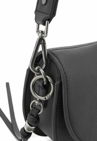 Dettaglio di una borsa a mano in pelle nera con finitura testurizzata, hardware in argento, clip e attacco circolare per la tracolla.