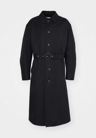 Černý trench coat s páskem, zapínáním na knoflíky, dlouhými rukávy a límcem, vyrobený z hladkého materiálu s matným povrchem.