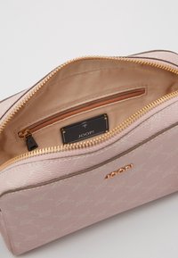 Rosa JOOP! necessär med guldkedja, beige tyginteriör och liten innerväska med dragkedja samt en svart märkesetikett.