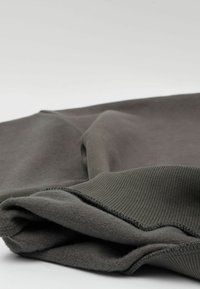 Szary sweatshirt o miękkiej fakturze, z prążkowanymi mankietami i płaskimi szwami wzdłuż brzegów, starannie złożony na neutralnym tle.