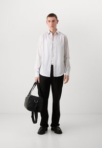 Camisa blanca de botones, pantalones negros y bolsa de cuero negro con una correa. Textura suave, diseño ajustado y zapatos negros pulidos.