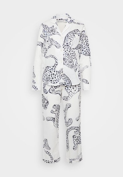 White pajama set featuring black leopard print. The shirt has a collar and buttons, while the pants have a relaxed fit and no cuffs.