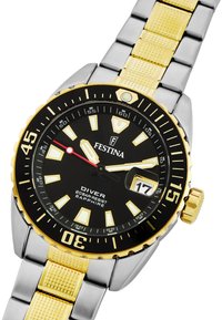 Nirtotājs ar melnu ciparnīcu, zelta akcentiem, nerūsējošā tērauda un zeltainu aproci, datuma logu 3. vietā un fosforesējošiem stundu marķieriem.